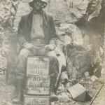 Miner sitting on dynamite boxes